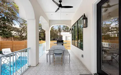 a patio with a table and chairs and a pool at Sapphire Bay by Oversee 30A in Santa Rosa Beach