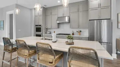 a kitchen with white cabinets and a large island with chairs at Queen Palm in Inlet Beach