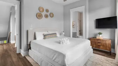 a white bedroom with a bed and a flat screen tv at Queen Palm in Inlet Beach