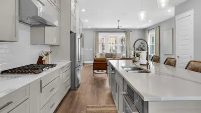 a kitchen with white countertops and a living room at Queen Palm in Inlet Beach