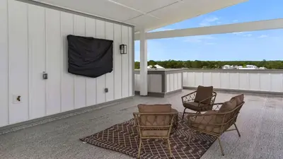 a porch with chairs and a screen on the wall at Queen Palm in Inlet Beach
