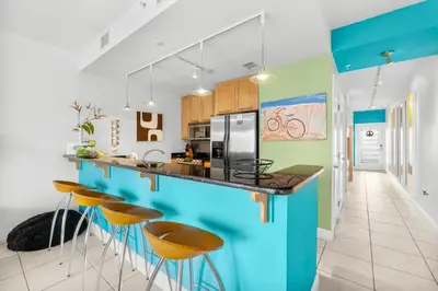 a kitchen with a blue island with bar stools at 30A - Cassine Station by Panhandle Getaways in Santa Rosa Beach