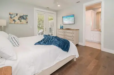 a bedroom with a white bed with a blue blanket on it at Chic Seagrove Retreat- Modern 30A Coastal Living in Santa Rosa Beach