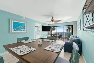a living room with a table and a blue wall at Commodore 202 - Thomas Drive Paradise in Panama City Beach