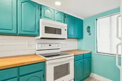 a kitchen with blue cabinets and a white microwave at Commodore 202 - Thomas Drive Paradise in Panama City Beach