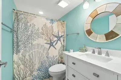 a bathroom with a sink and a toilet and a mirror at Commodore 202 - Thomas Drive Paradise in Panama City Beach
