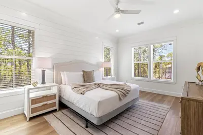a white bedroom with a bed and two windows at Coastal Opulence in Santa Rosa Beach