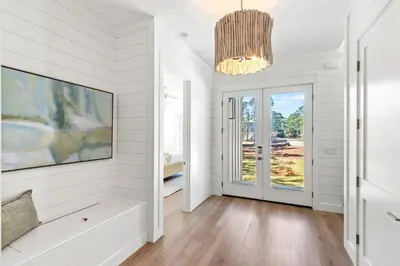 a living room with white walls and a chandelier at Coastal Opulence in Santa Rosa Beach