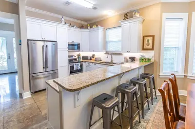 a kitchen with white cabinets and a large island with bar stools at Blue Paradise in Seagrove Beach