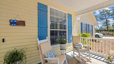 a yellow house with two chairs on a porch at 30A Cottage Near the Beach with Golf Cart in Inlet Beach