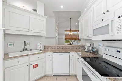 a white kitchen with white cabinets and appliances at Camp Seabreeze in Inlet Beach