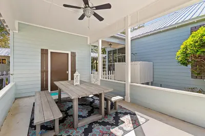a porch with a table and a ceiling fan at Camp Seabreeze in Inlet Beach