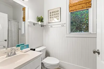 a white bathroom with a toilet and a sink at Camp Seabreeze in Inlet Beach
