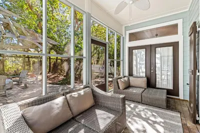 a screened in porch with a couch and windows at Camp Seabreeze in Inlet Beach