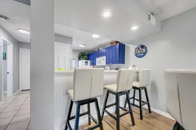 a kitchen with white stools and a counter at Edgewater Golf Villa 956 in Santa Rosa Beach