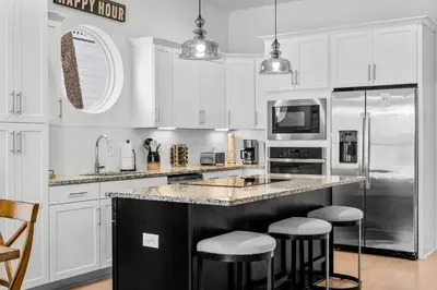 a kitchen with white cabinets and a large island with bar stools at 30A Pet Friendly Beach House - Paradise Valle by Panhandle Getaways in Inlet Beach