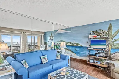 a living room with a blue couch and a painting at Pinnacle Port A-506 in Carillon Beach