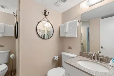 a bathroom with a toilet and a sink and a mirror at Pinnacle Port A-730 in Carillon Beach