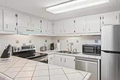 a kitchen with white cabinets and stainless steel appliances at Pinnacle Port A-701 in Carillon Beach