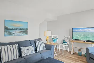 a living room with a couch and a flat screen tv at Pinnacle Port A-701 in Carillon Beach