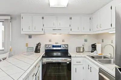 a kitchen with white cabinets and a stove top oven at Pinnacle Port A-701 in Carillon Beach