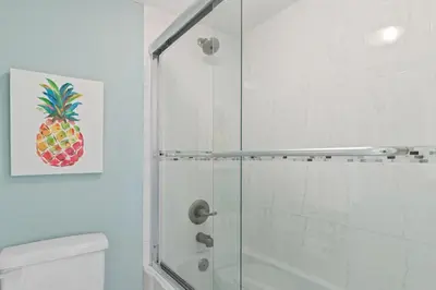 a bathroom with a shower with a pineapple painting on the wall at Pinnacle Port, A-708 in Carillon Beach