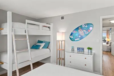 a bedroom with bunk beds with a surfboard on the wall at Pinnacle Port, A-708 in Carillon Beach