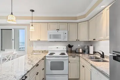 a kitchen with white cabinets and a white stove top oven at Pinnacle Port, A-708 in Carillon Beach