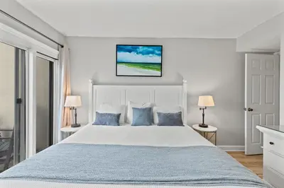 a bedroom with a large bed with blue pillows at Pinnacle Port, A-708 in Carillon Beach