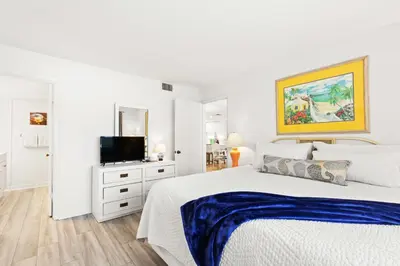 a white bedroom with a bed and a flat screen tv at Pinnacle Port C1-401 in Carillon Beach