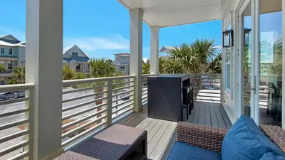 a porch with chairs and a television on a balcony at The Bee's Knees in Santa Rosa Beach