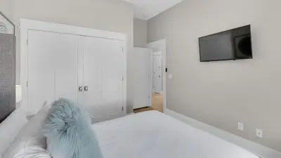 a white bedroom with a bed and a tv at The Bee's Knees in Santa Rosa Beach