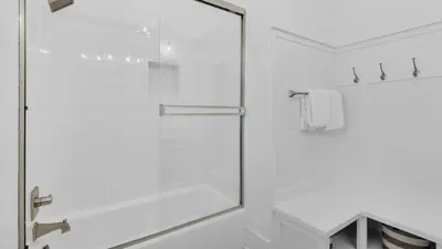 a glass shower door in a white bathroom at The Bee's Knees in Santa Rosa Beach