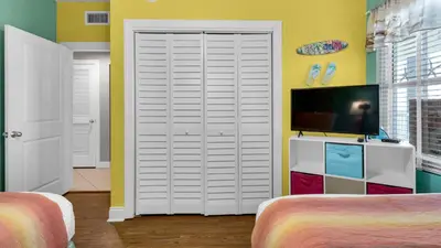 a bedroom with two beds and a tv and a white door at Palazzo 806 in Panama City Beach
