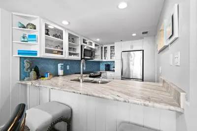 a kitchen with white cabinets and a marble counter top at One Seagrove Place 1504 in Santa Rosa Beach