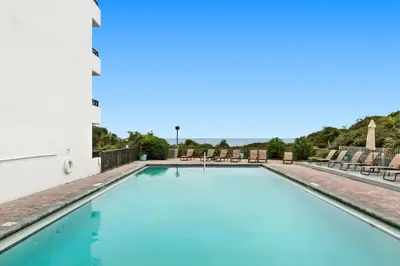 a swimming pool with chairs and tables at One Seagrove Place 1504 in Santa Rosa Beach