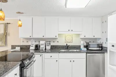 a white kitchen with white cabinets and appliances at Pinnacle Port, C1-303 in Panama City Beach