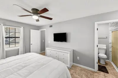 a white bedroom with a bed and a ceiling fan at Condo w/beach, pools, tennis, shuffleboard, more! in Panama City Beach