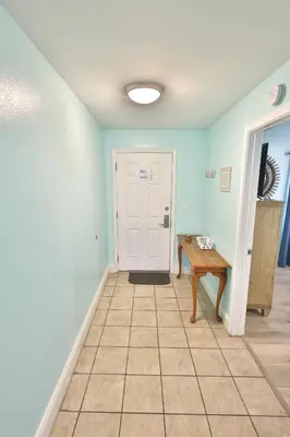 a hallway with a white door and a table at Lake Town Charming Condo Steps from the Beach in Panama City Beach