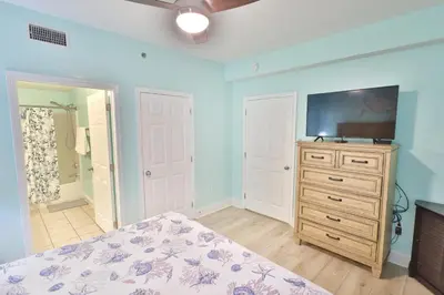 a bedroom with a bed and a dresser with a tv at Lake Town Charming Condo Steps from the Beach in Panama City Beach
