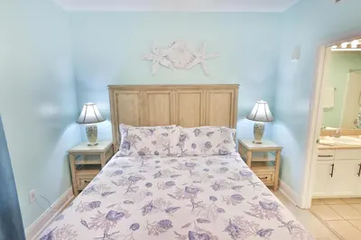 a bed in a bedroom with two night stands and two lamps at Lake Town Charming Condo Steps from the Beach in Panama City Beach