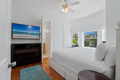 a white bedroom with a bed and a flat screen tv at Ocean Glory 30A in Inlet Beach