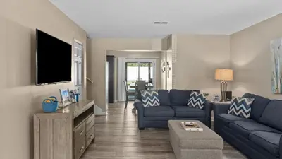a living room with a blue couch and a tv at PCB Group-Friendly Duplex w Pool Backyard Lounge 2 Kitchens in Panama City Beach