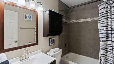 a bathroom with a sink and a toilet and a mirror at PCB Group-Friendly Duplex w Pool Backyard Lounge 2 Kitchens in Panama City Beach