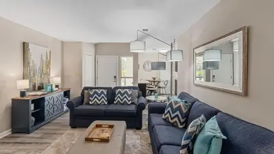 a living room with two blue couches and a table at PCB Group-Friendly Duplex w Pool Backyard Lounge 2 Kitchens in Panama City Beach