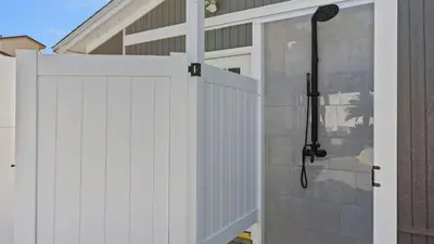 a white privacy fence with a shower in a house at PCB Group-Friendly Duplex w Pool Backyard Lounge 2 Kitchens in Panama City Beach