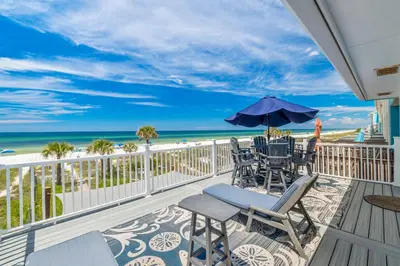a balcony with chairs and an umbrella and the beach at Beachside West Villa #2 by Emerald Coast Retreats in Panama City Beach