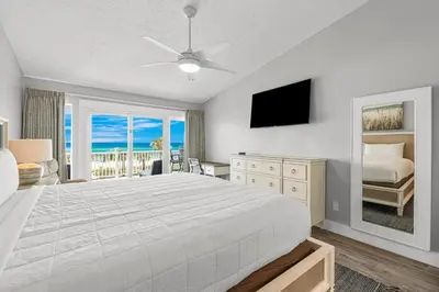 a bedroom with a bed and a television and a balcony at Beachside West Villa #2 by Emerald Coast Retreats in Panama City Beach