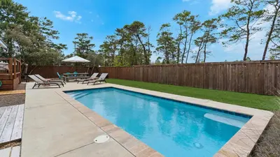 a swimming pool in a backyard with a wooden fence at Coastal Charm in Santa Rosa Beach