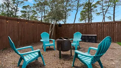 four chairs and a grill in a yard with a fence at Coastal Charm in Santa Rosa Beach